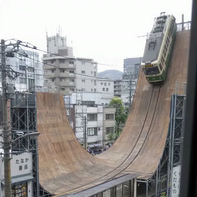 街なかに組まれた巨大なハーフパイプを、広電の電車が走っている場面