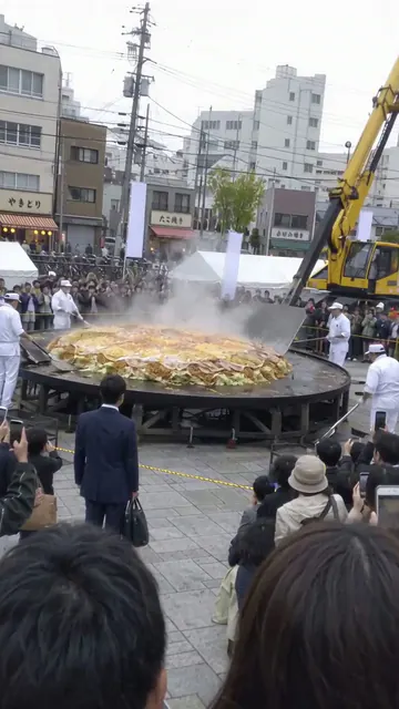 クレーンで巨大なお好み焼きをひっくり返そうとしている場面